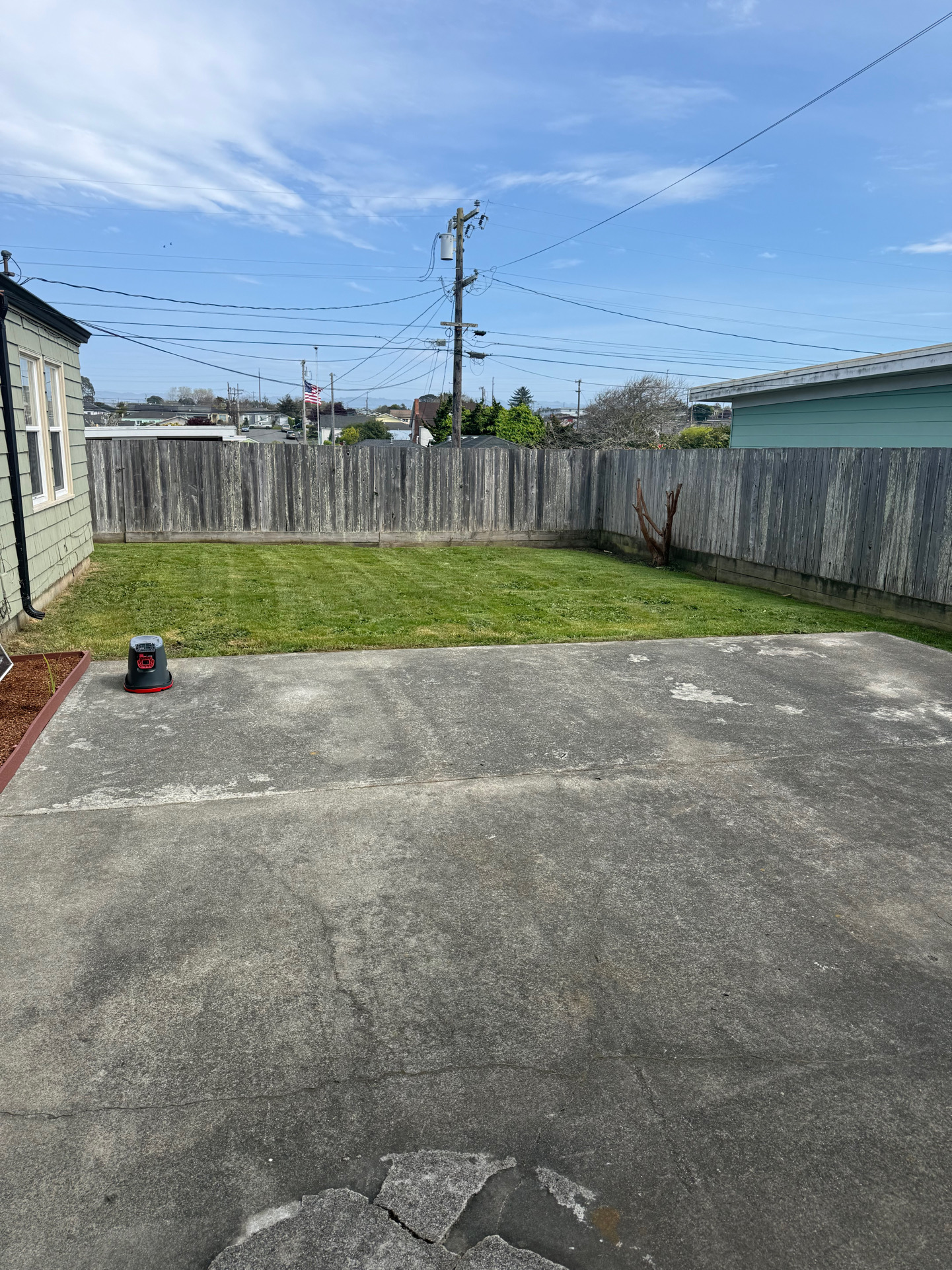 Clean Humboldt County backyard with fresh green lawn and pressure-washed concrete patio by Rodriguez Landscaping
